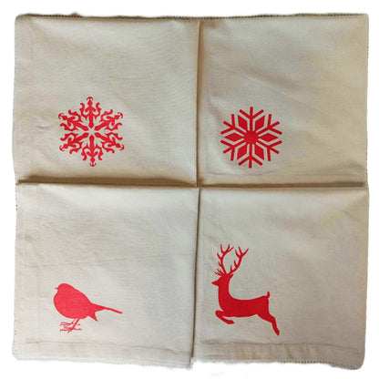 Four folded SeaNic Christmas napkins — Stag, Robin, Traditional Snowflake and Nordic Snowflake — hand-printed on organic cotton in Devon for a sustainable festive table.