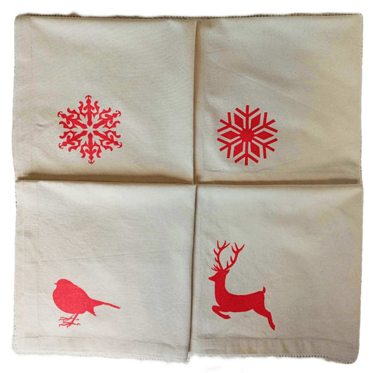 Four folded SeaNic Christmas napkins — Stag, Robin, Traditional Snowflake and Nordic Snowflake — hand-printed on organic cotton in Devon for a sustainable festive table.