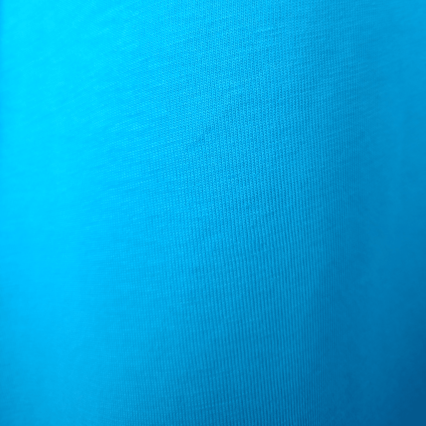 Close-up of bright blue GOTS organic cotton fabric texture showing high-quality knit for SeaNic sustainable t-shirts.